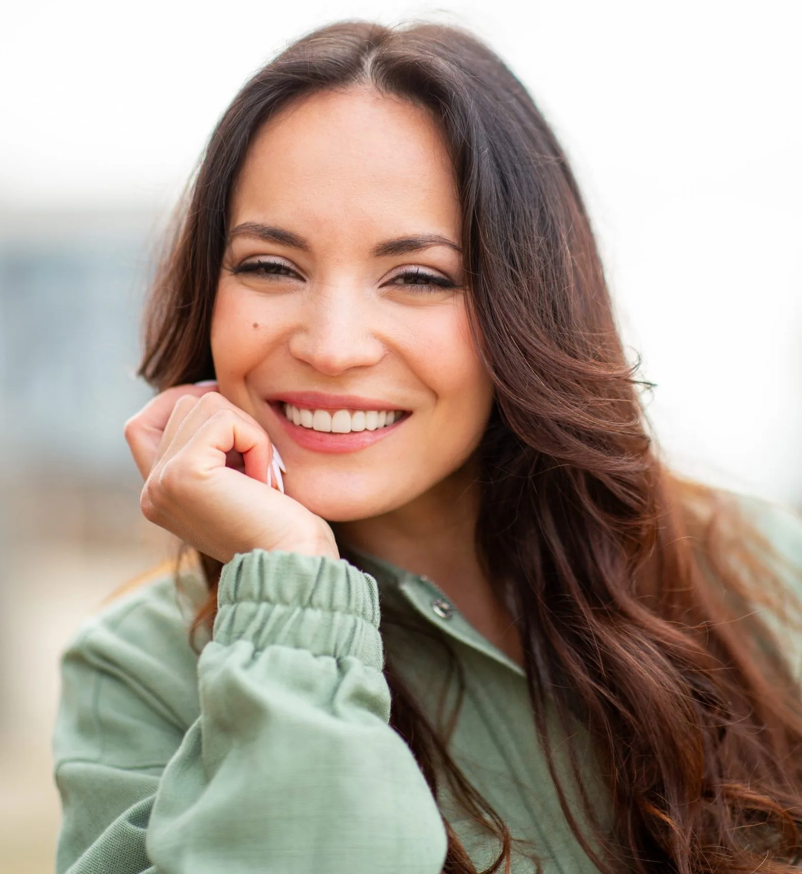 Woman in green jacket smiling outdoors with healthy complexion