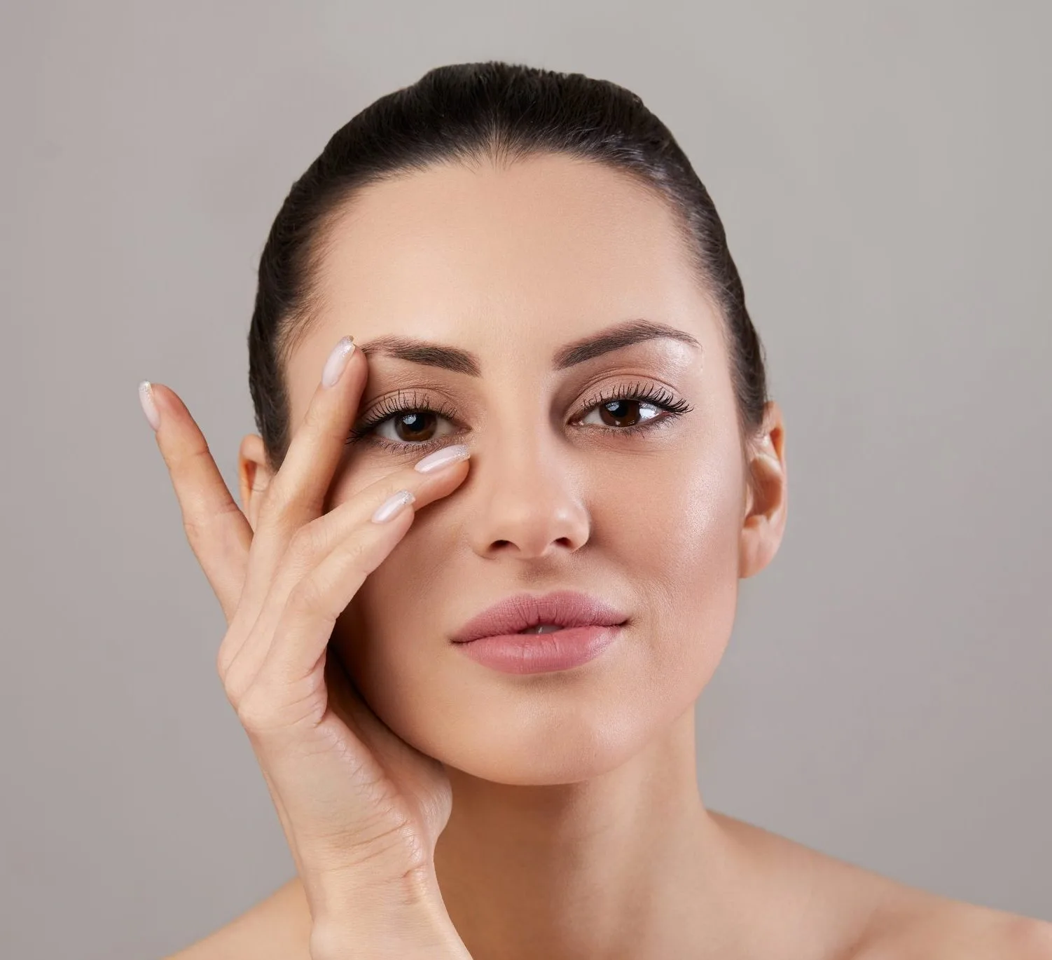 Woman applying moisturizer around her eye area with her fingertip