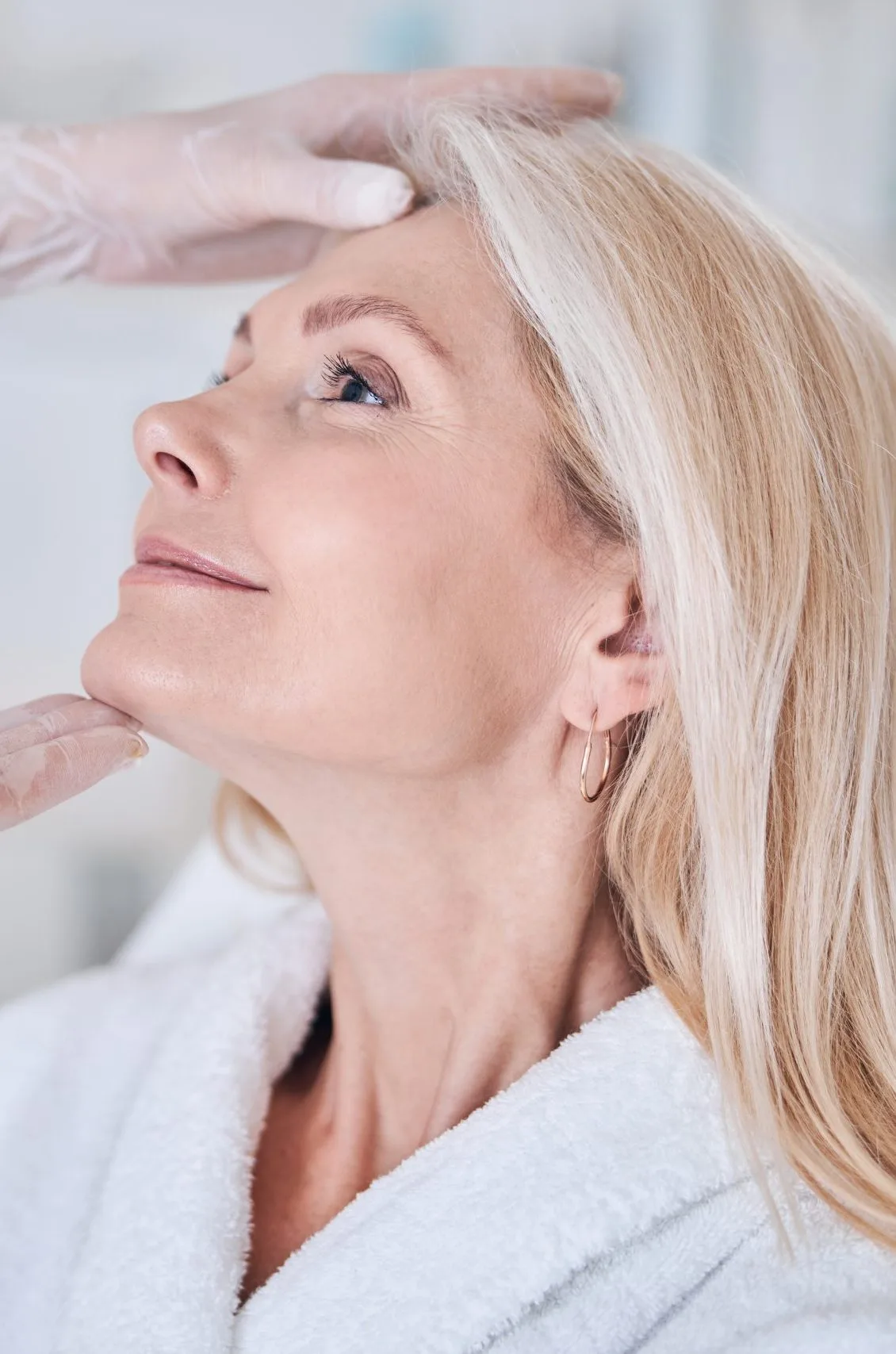 Practitioner examining patient's jawline and chin area during facial assessment