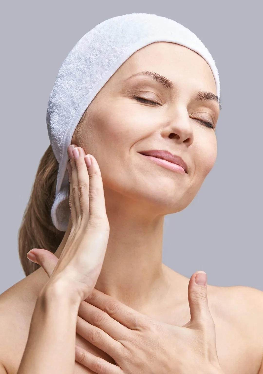 Woman wearing white headband touching her face with eyes closed