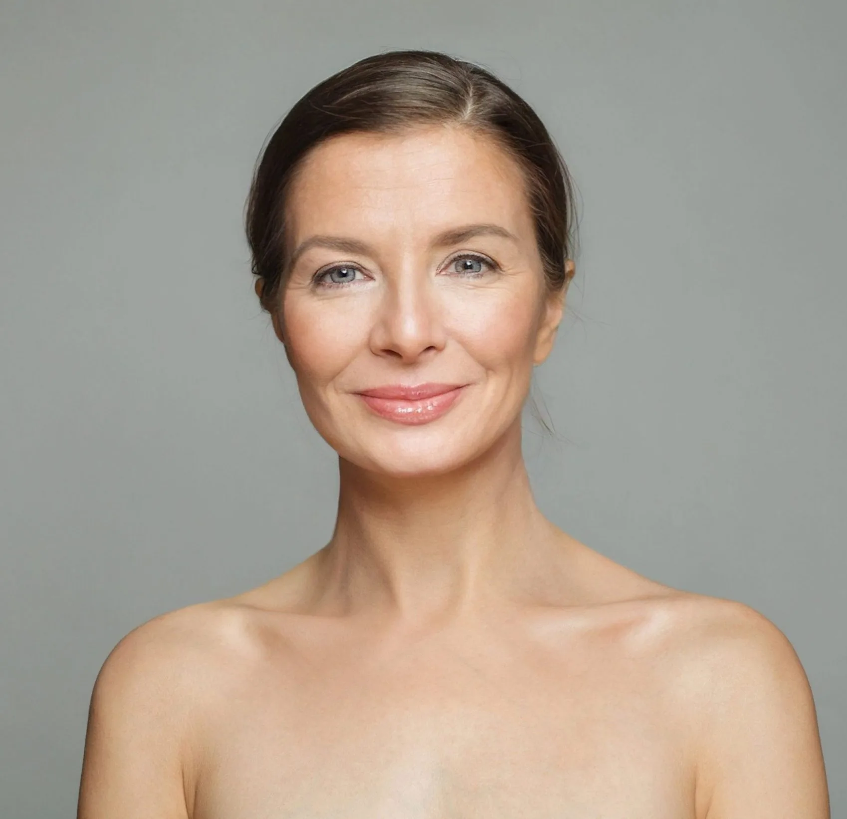 Woman with smooth skin and pink lips facing camera against gray background