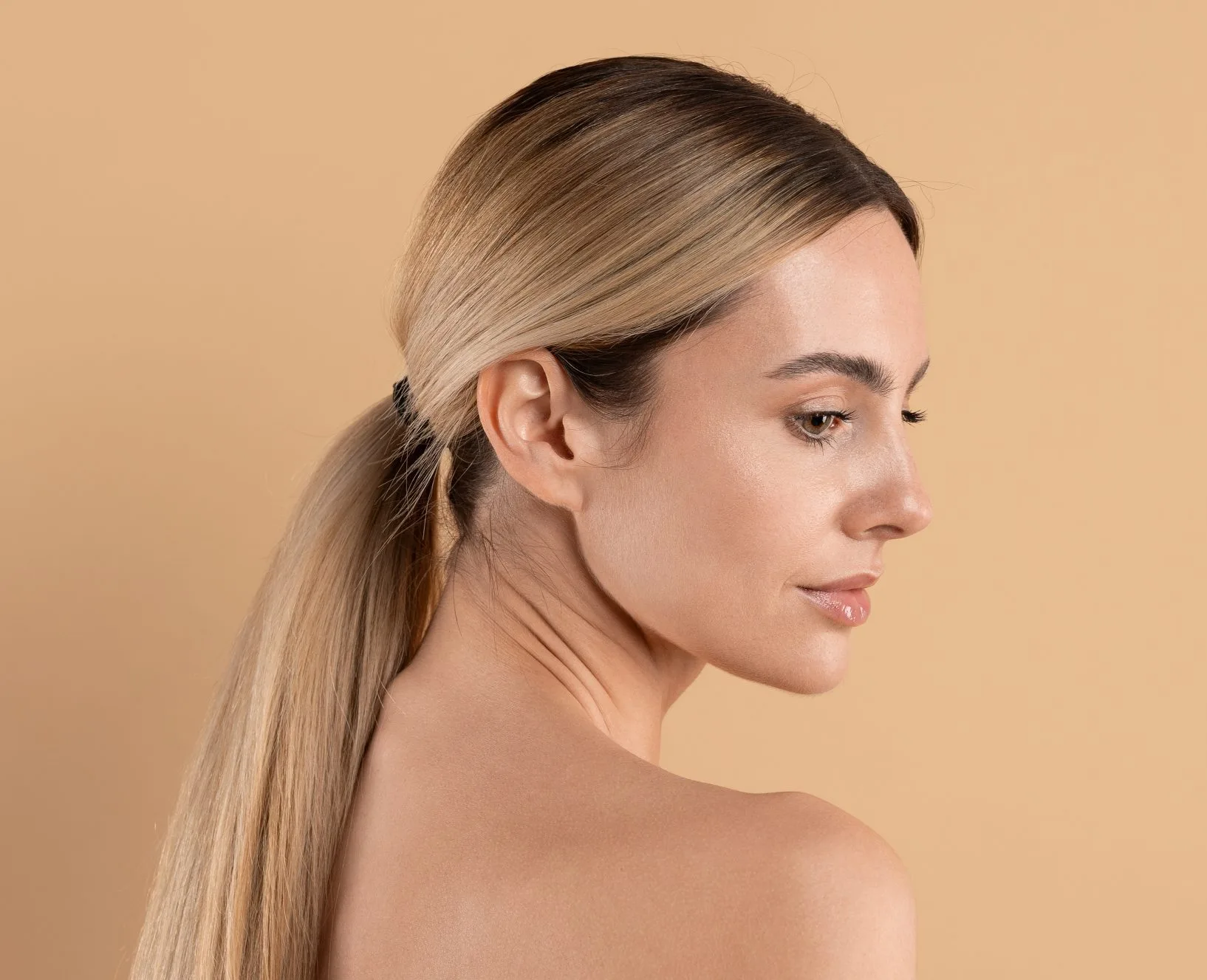 Woman with blonde hair in profile against neutral background