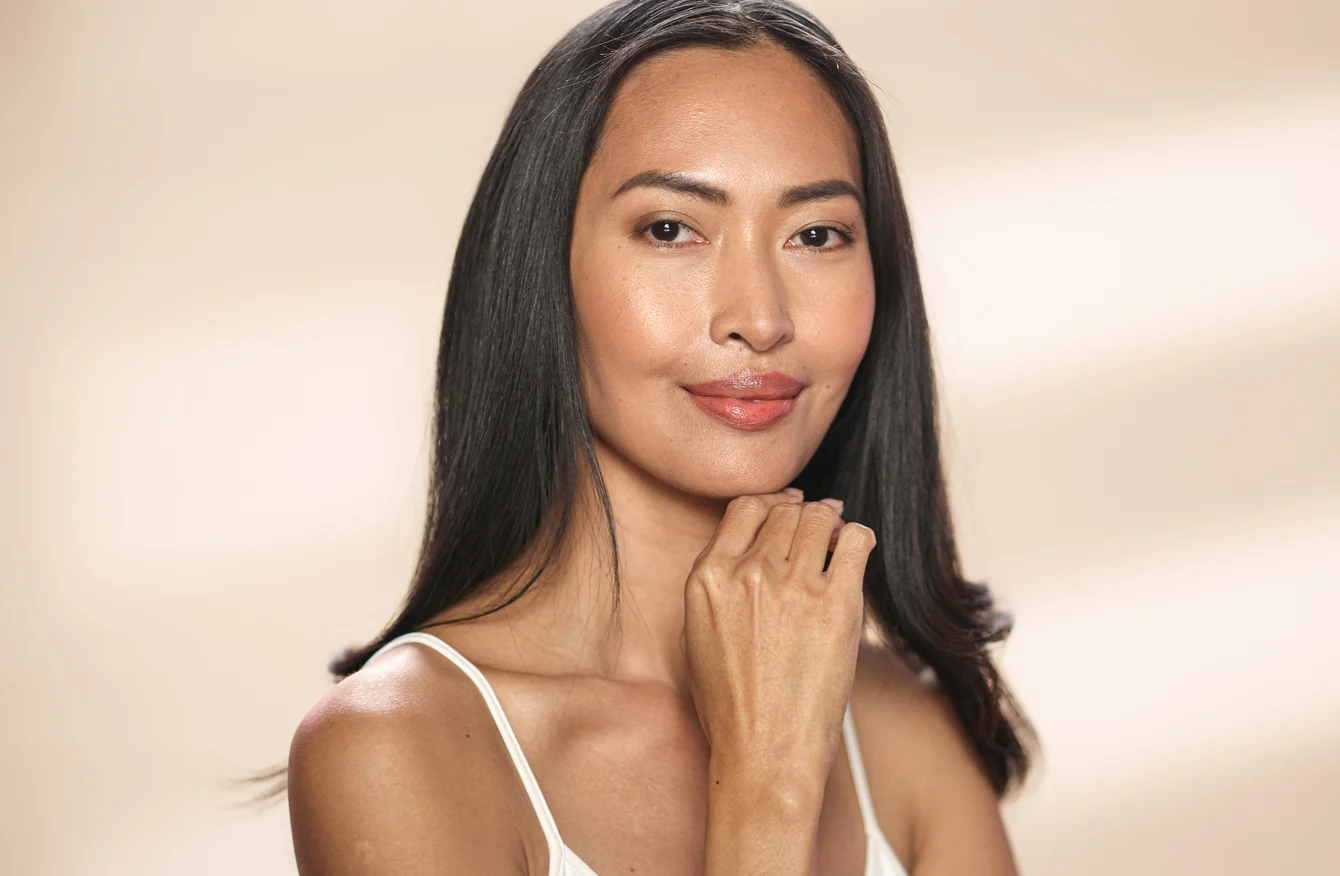 Woman with radiant skin resting her hand at her chin