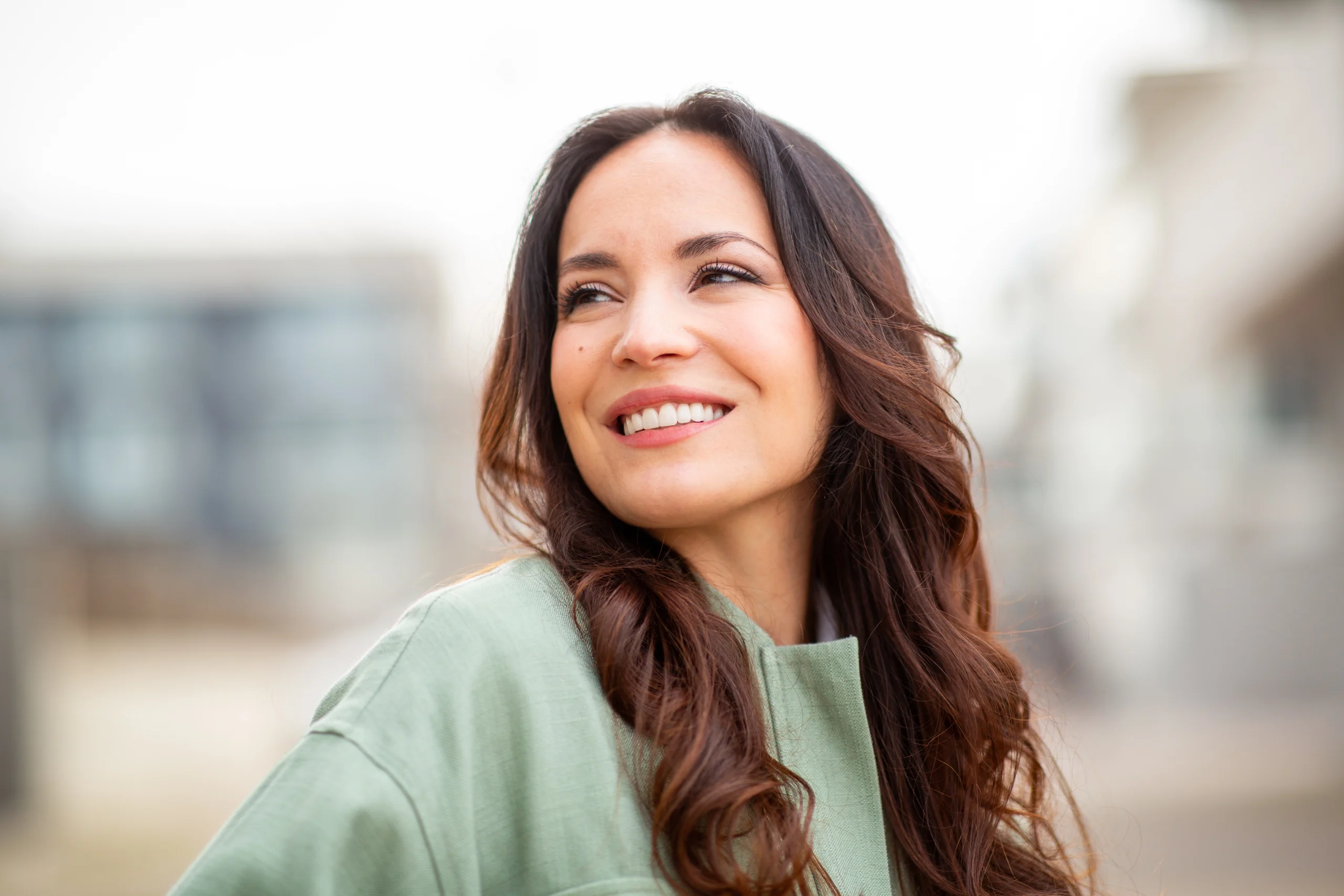 Woman with long wavy hair smiling in soft outdoor light