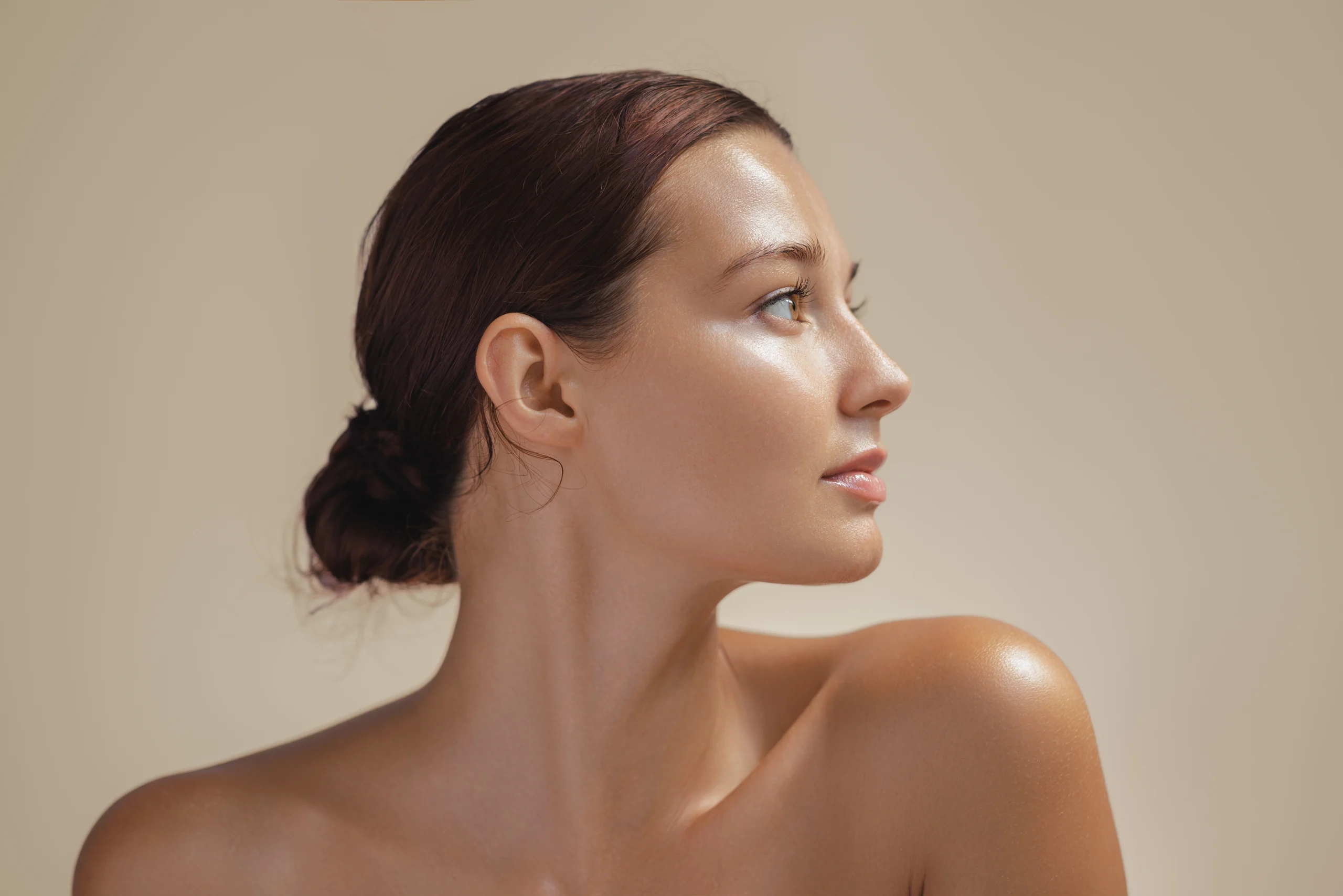 Woman in her late thirties shown in profile with hair pulled back, glowing skin