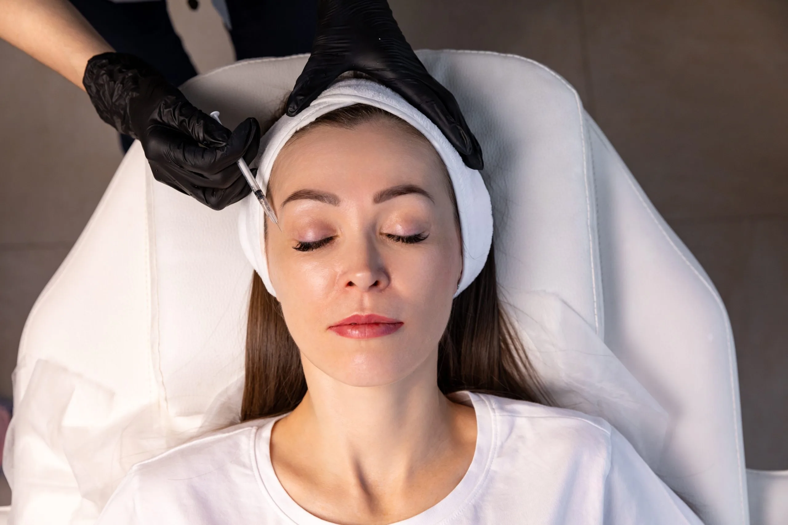 Woman receiving Botox injection to forehead during anti-aging treatment